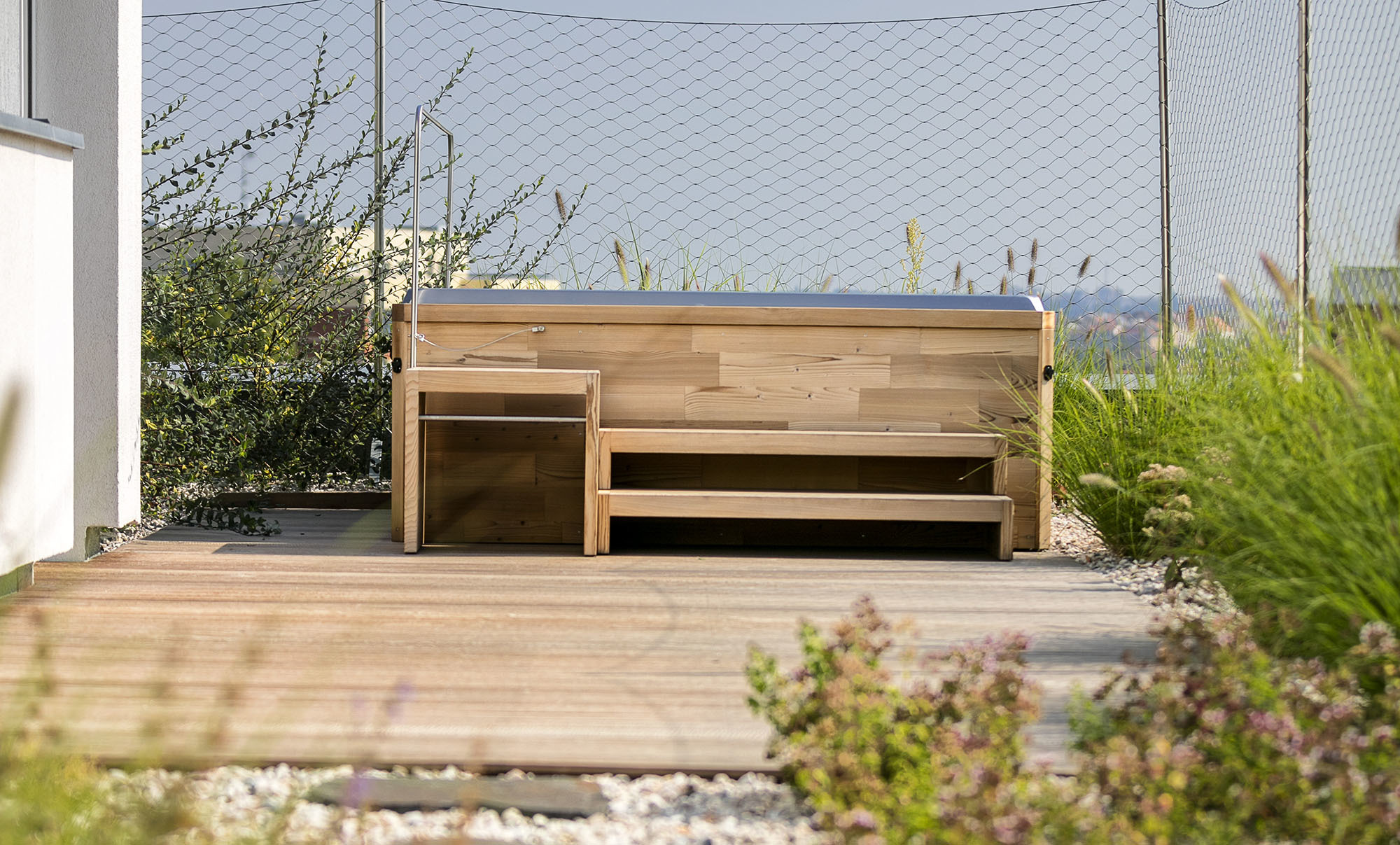 Holzaußenverkleidung eines Premium-Whirlpools von USSPA auf einer Terrasse mit umgebenden Pflanzungen, angeboten von ActiveSpa GmbH.