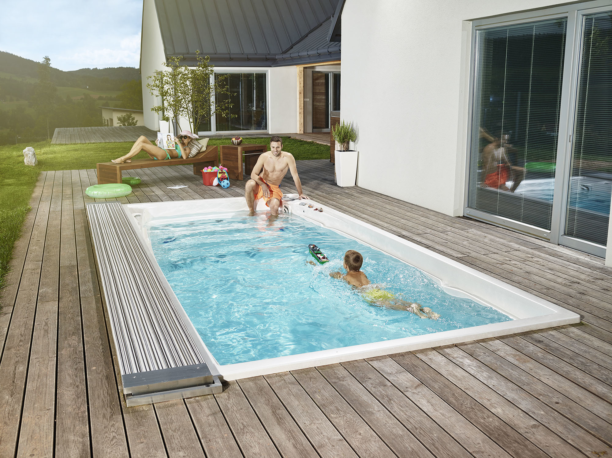 Premium USSPA Swim Spa von ActiveSpa auf einer Holzterrasse im Garten: Familie genießt gemeinsame Zeit durch Schwimmen und Entspannung.