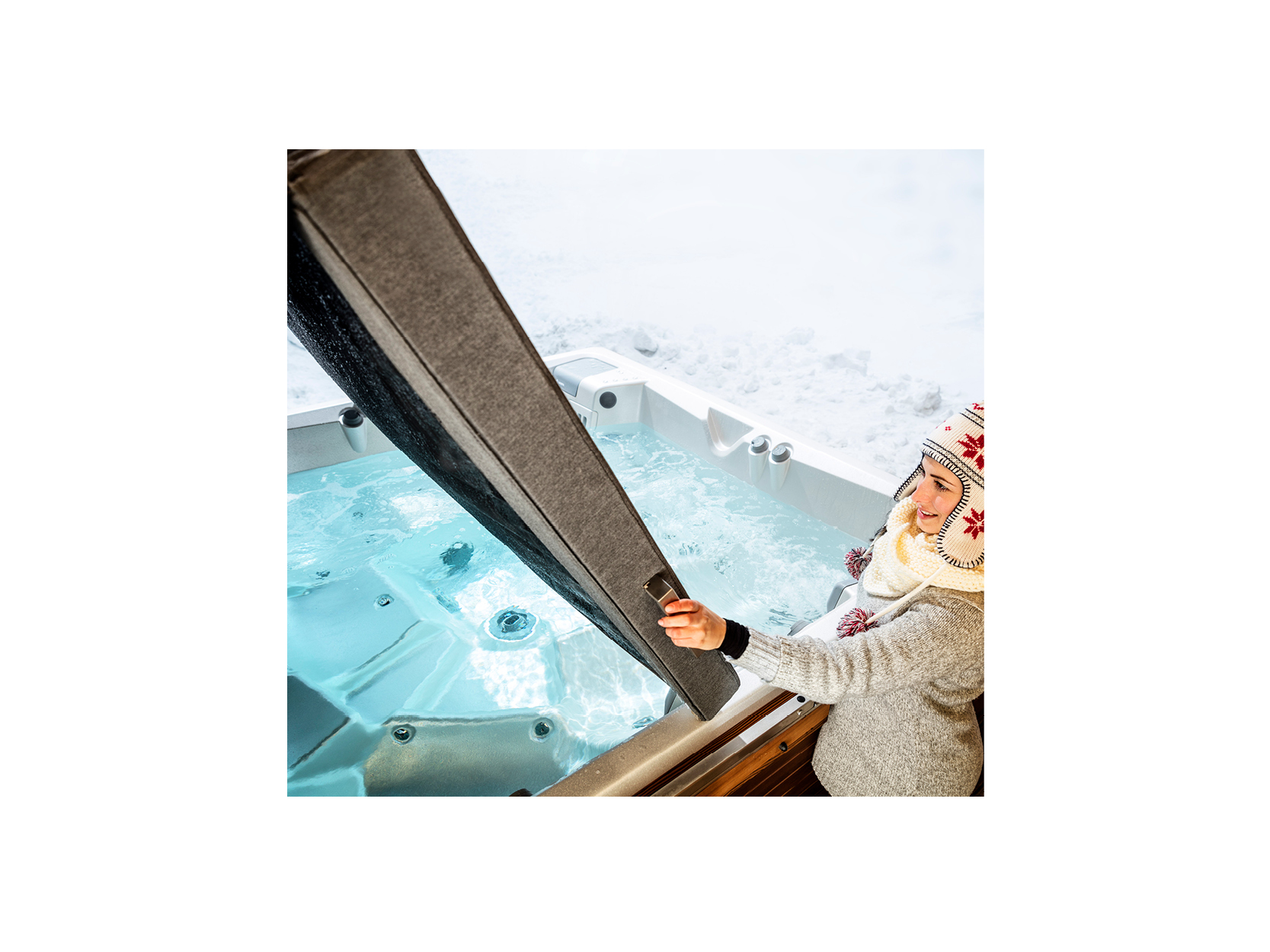 Person öffnet die Isolierabdeckung eines hochwertigen Whirlpools von ActiveSpa in einer schneebedeckten Umgebung, ideal für private Entspannung und Wellness.