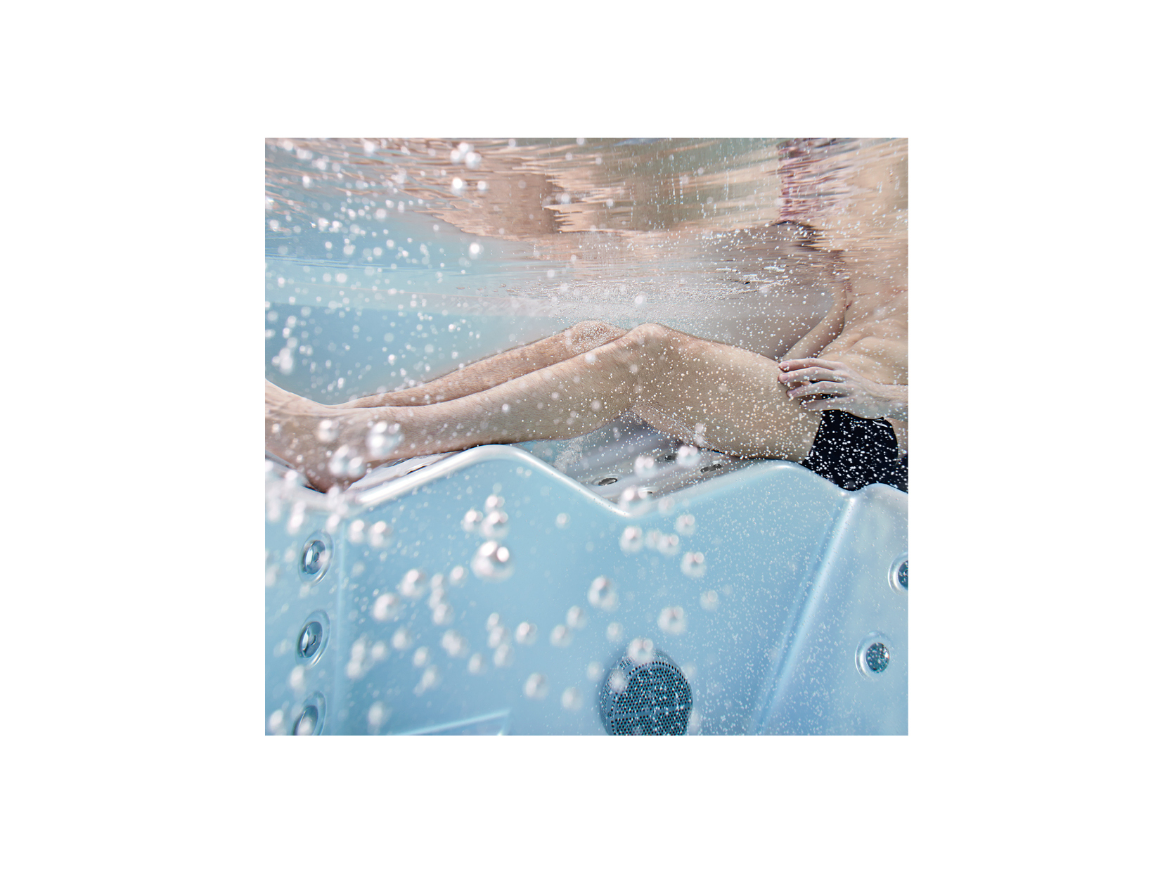 Unterwasseransicht eines Menschen, der sich in einem USSPA Premium-Whirlpool mit sprudelnden Blasen entspannt – ein Beispiel für hydrotherapeutische Entspannung und Wohlbefinden.